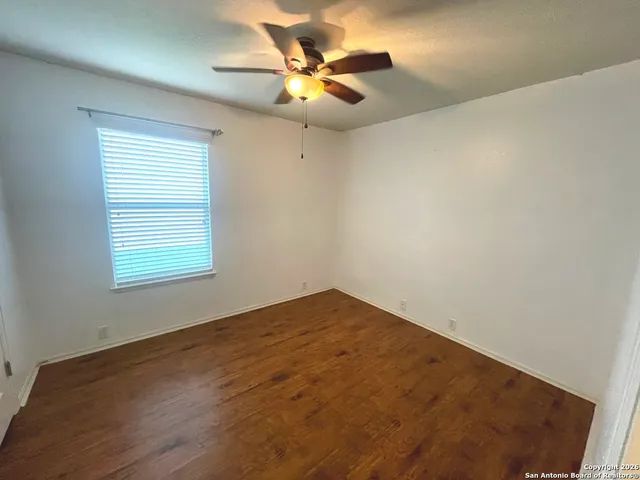 an empty room with a window and a ceiling fan