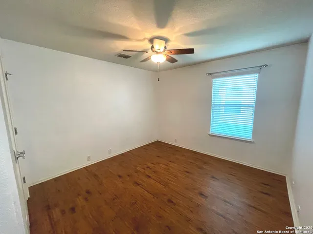 an empty room with a window and a ceiling fan