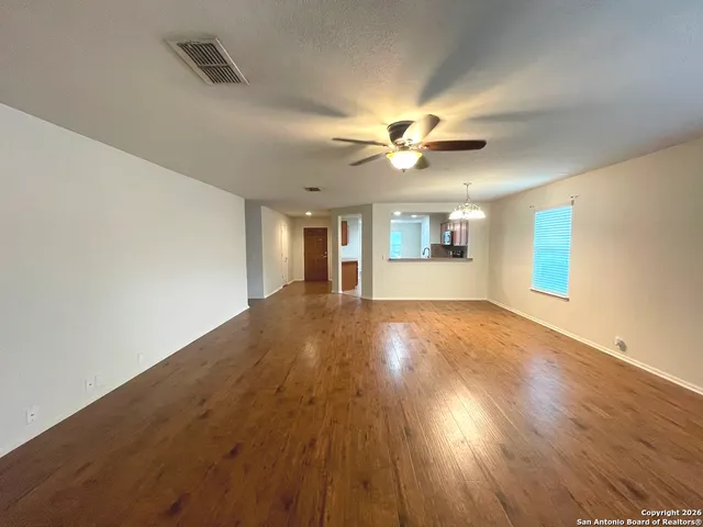 a view of an empty room with window and wooden floor