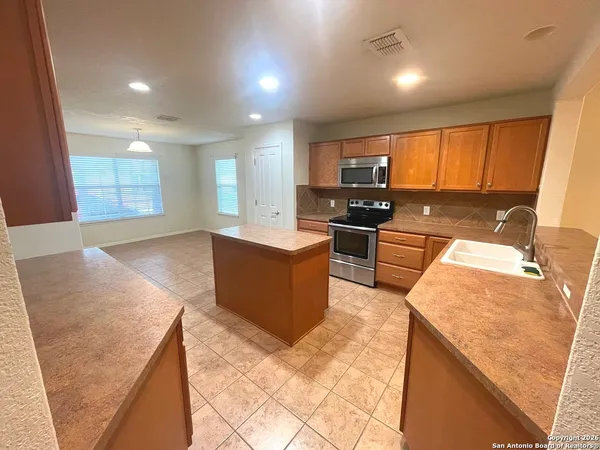 a large kitchen with stainless steel appliances kitchen island granite countertop a sink and cabinets