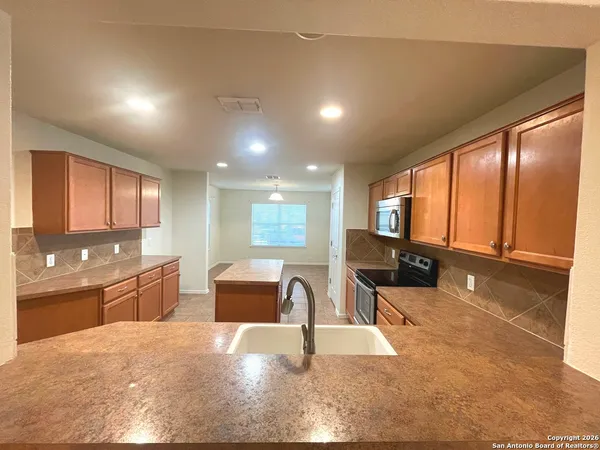a large hall with stainless steel appliances granite countertop a sink and cabinets