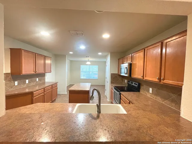 a large hall with stainless steel appliances granite countertop a sink and cabinets