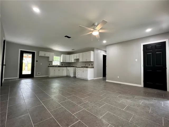 a view of an empty room with kitchen and window