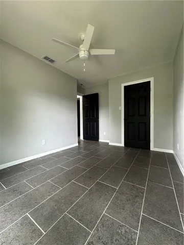 a view of an empty room with a ceiling fan and window