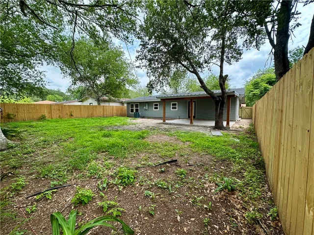 a front view of a house with a yard and a large tree