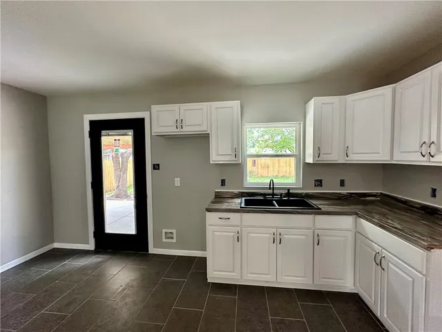 a kitchen with granite countertop white cabinets and window
