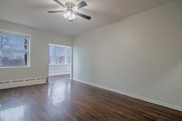 a view of an empty room with window and wooden floor