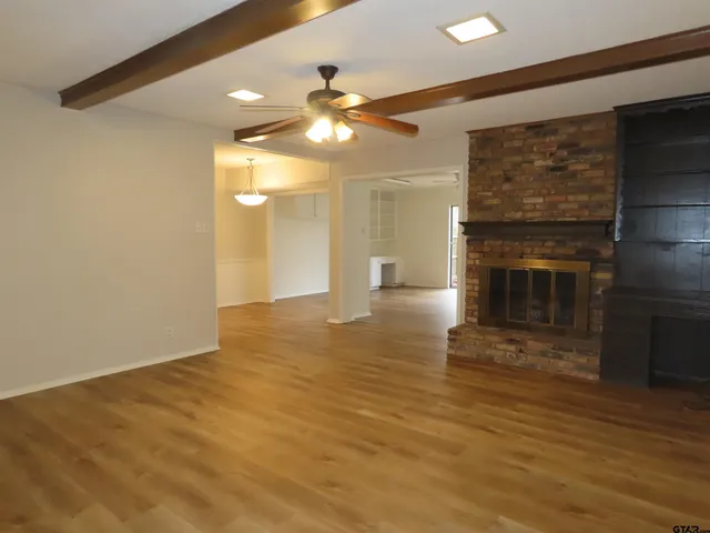 a view of an empty room with wooden floor and a fireplace