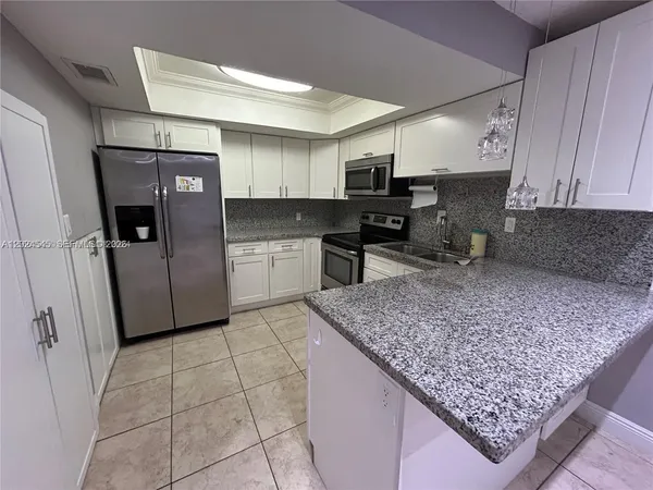 a kitchen with stainless steel appliances granite countertop a refrigerator sink and stove