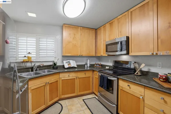 a kitchen with stainless steel appliances granite countertop a sink a stove a microwave cabinets and a window