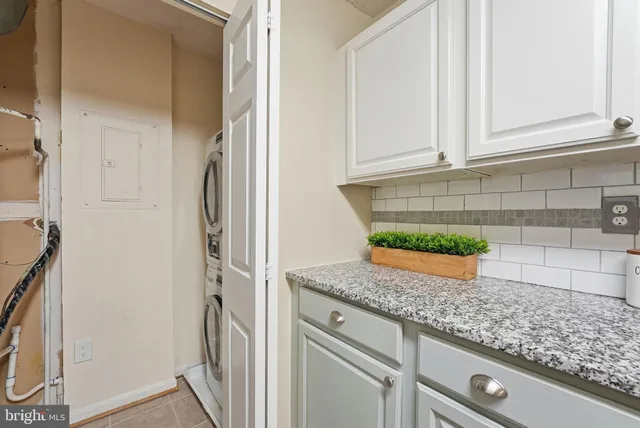 a kitchen with granite countertop white cabinets and a refrigerator