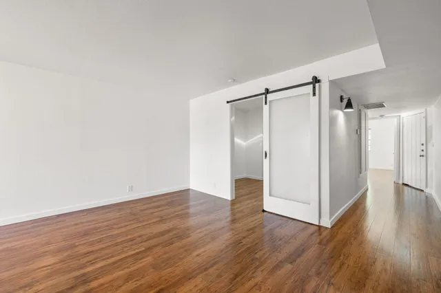 a view of an empty room with wooden floor and a window