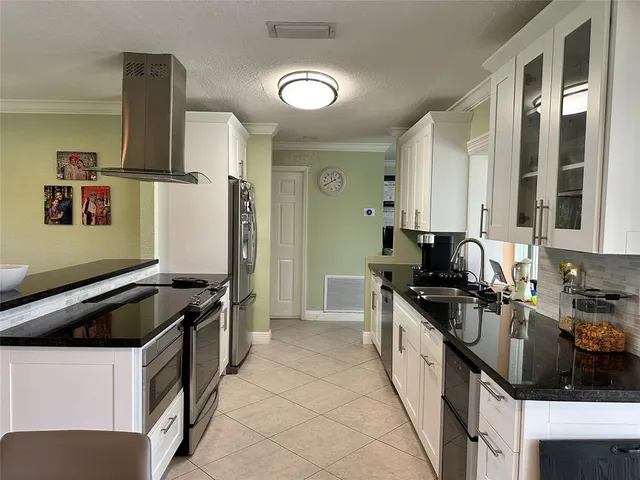 a kitchen with granite countertop a sink a stove and refrigerator