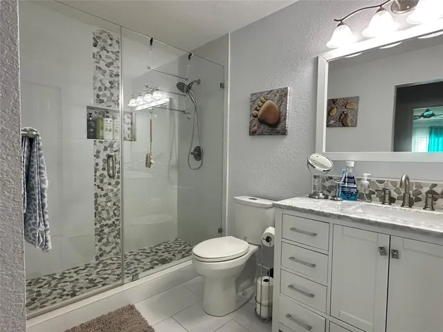 a bathroom with a toilet a sink a mirror and shower