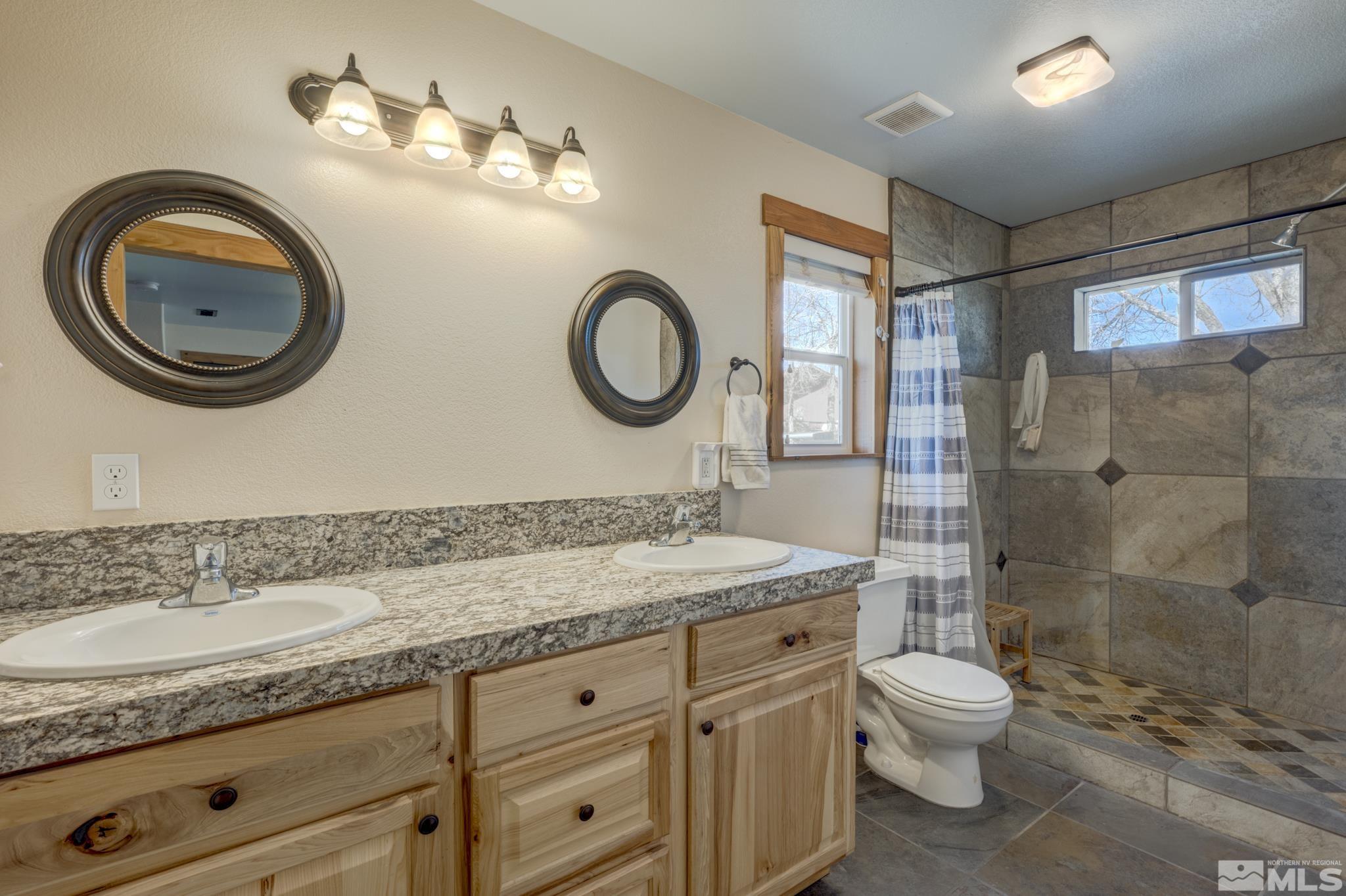 10500 Wells Fargo Road Reno, NV 89508 - Photo 16 of 37 a bathroom with a granite countertop double vanity sink mirror and toilet