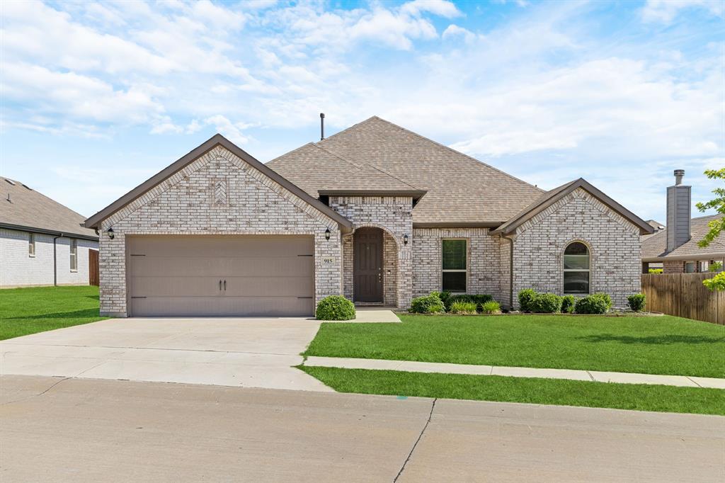 915 Timber Ridge Drive Justin, TX 76247 - Photo 1 of 39 Brick-clad residence featuring an arched entry, a two-car garage with a panel door, a gabled roofline, and an arched window