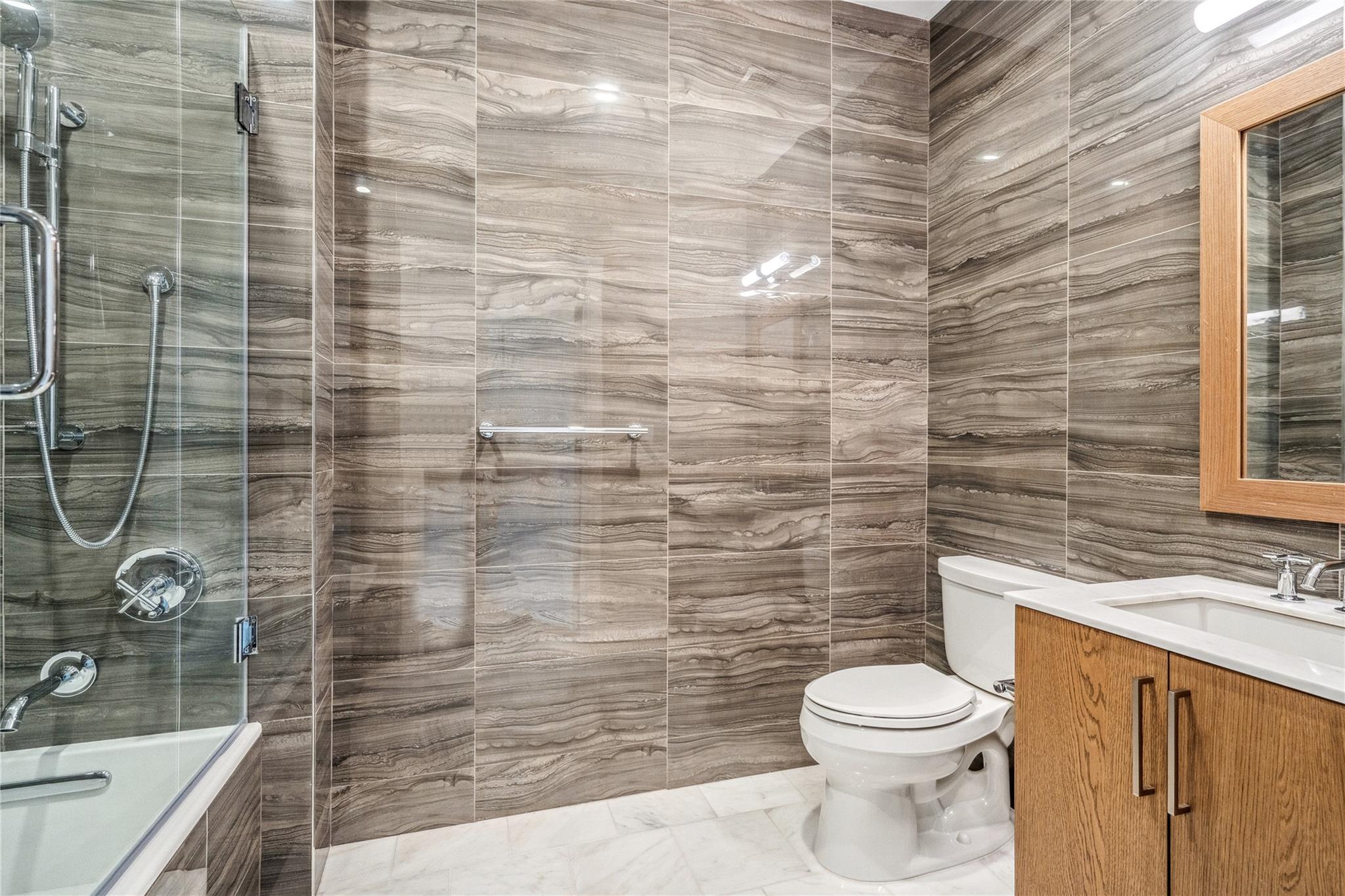 100 Garvies Point Road, Unit 1126 Glen Cove, NY 11542 - Photo 12 of 40 Full bathroom featuring vanity, enclosed tub / shower combo, tile walls, and toilet