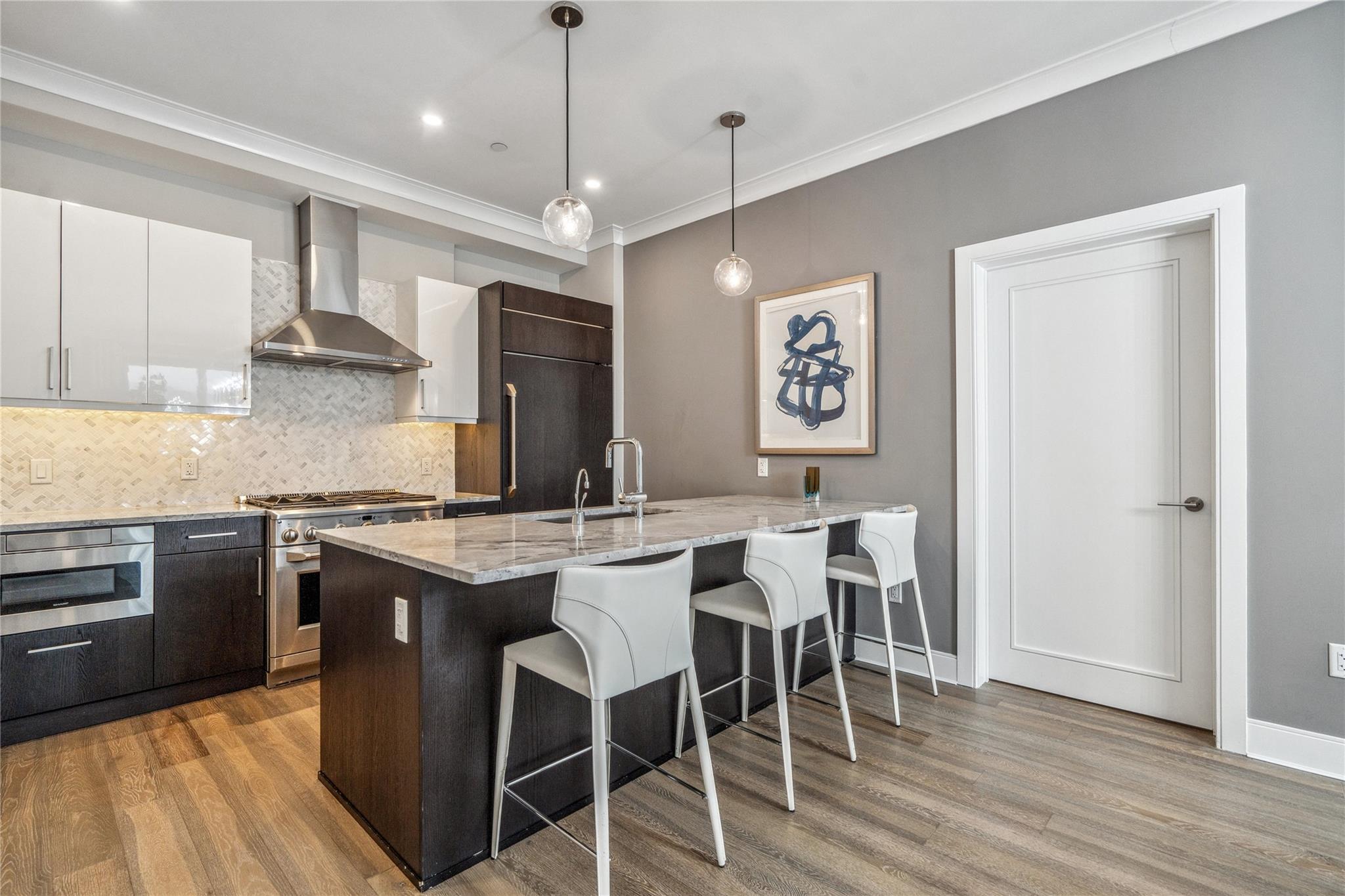 100 Garvies Point Road, Unit 1126 Glen Cove, NY 11542 - Photo 20 of 40 Kitchen featuring high end appliances, sink, wall chimney range hood, pendant lighting, and white cabinetry