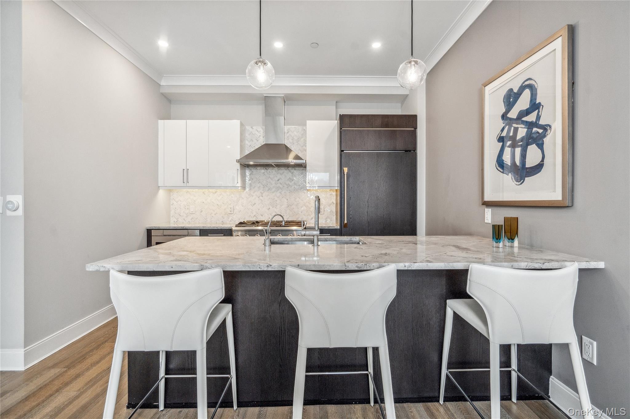 100 Garvies Point Road, Unit 1126 Glen Cove, NY 11542 - Photo 21 of 40 Kitchen featuring dark wood-type flooring, white cabinets, wall chimney exhaust hood, ornamental molding, and decorative light fixtures