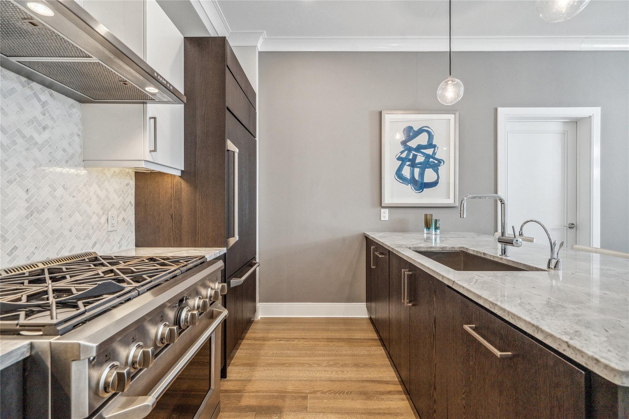100 Garvies Point Road, Unit 1126 Glen Cove, NY 11542 - Photo 23 of 40 Kitchen featuring high end range, light wood-type flooring, sink, wall chimney range hood, and hanging light fixtures
