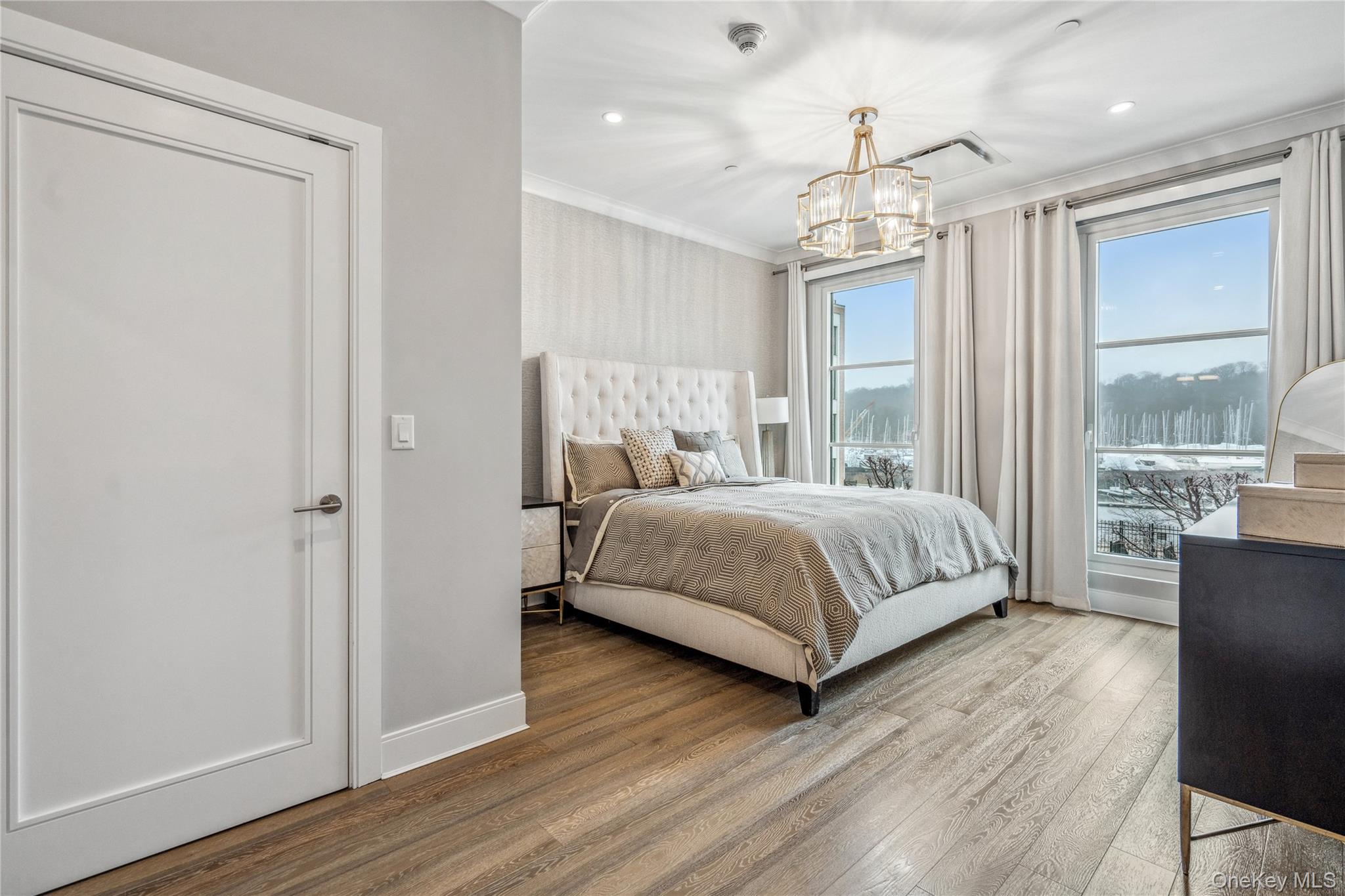100 Garvies Point Road, Unit 1126 Glen Cove, NY 11542 - Photo 25 of 40 Bedroom featuring hardwood / wood-style flooring, a notable chandelier, and crown molding