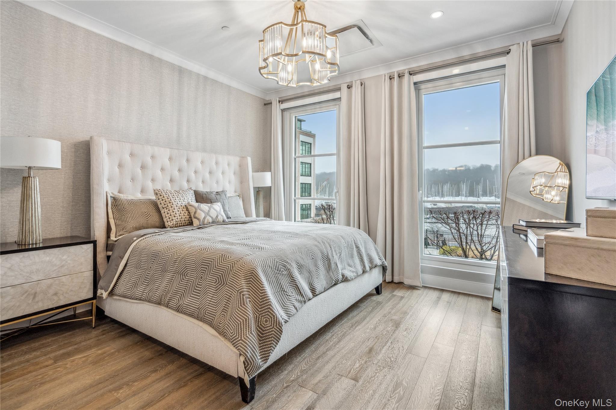 100 Garvies Point Road, Unit 1126 Glen Cove, NY 11542 - Photo 26 of 40 Bedroom with hardwood / wood-style flooring, an inviting chandelier, and multiple windows