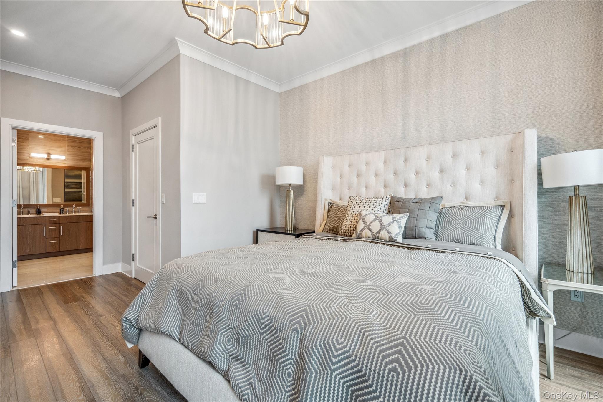 100 Garvies Point Road, Unit 1126 Glen Cove, NY 11542 - Photo 27 of 40 Bedroom featuring ensuite bath, ornamental molding, sink, an inviting chandelier, and hardwood / wood-style floors