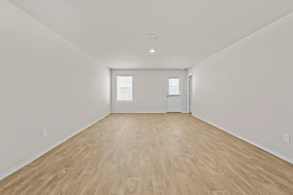 a view of an empty room with wooden floor and windows