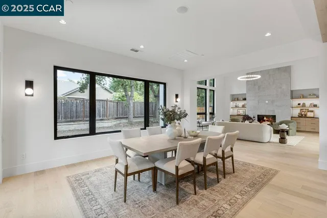 a dining room with wooden floor and large windows