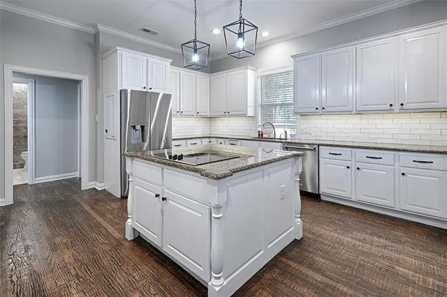 a kitchen with kitchen island granite countertop a sink cabinets and stainless steel appliances