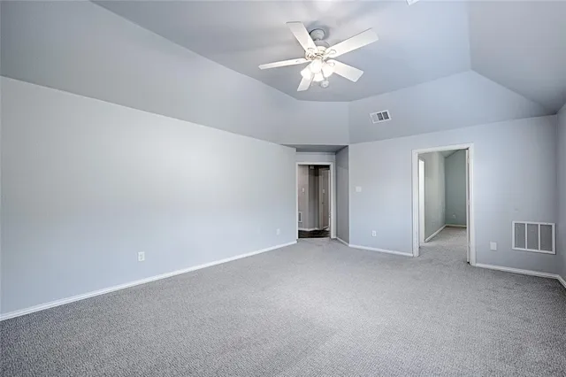 an empty room with chandelier fan and windows