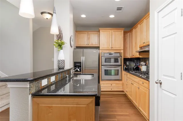 a kitchen with stainless steel appliances granite countertop a sink a stove and refrigerator