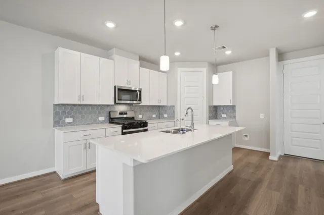 a kitchen with a sink a stove a microwave a center island and cabinets