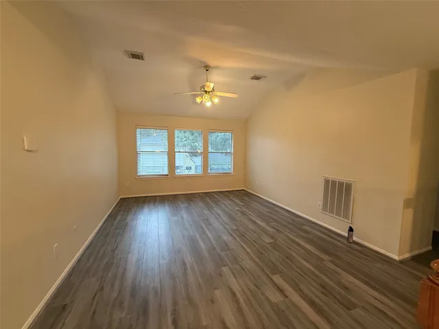 a view of a room with wooden floor and a ceiling fan