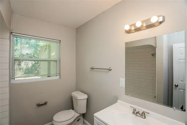 a bathroom with a toilet a sink a mirror and a window