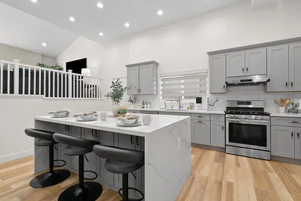 a kitchen with stainless steel appliances kitchen island a table chairs in it and wooden floors