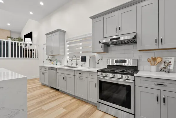 a kitchen with stainless steel appliances granite countertop a stove a sink and a white cabinets