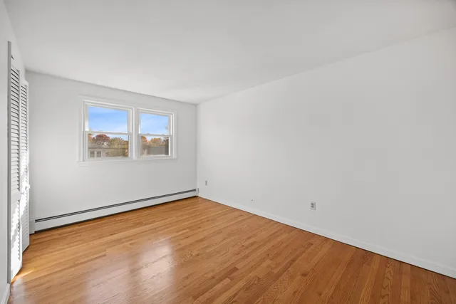 an empty room with a wooden floor and windows