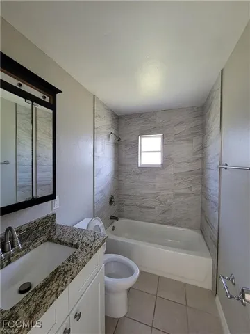 a bathroom with a granite countertop sink a toilet a mirror and bathtub