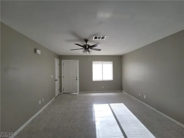 an empty room with windows and fan