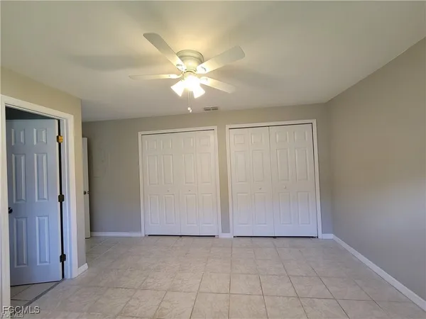 an empty room with closet and a chandelier fan