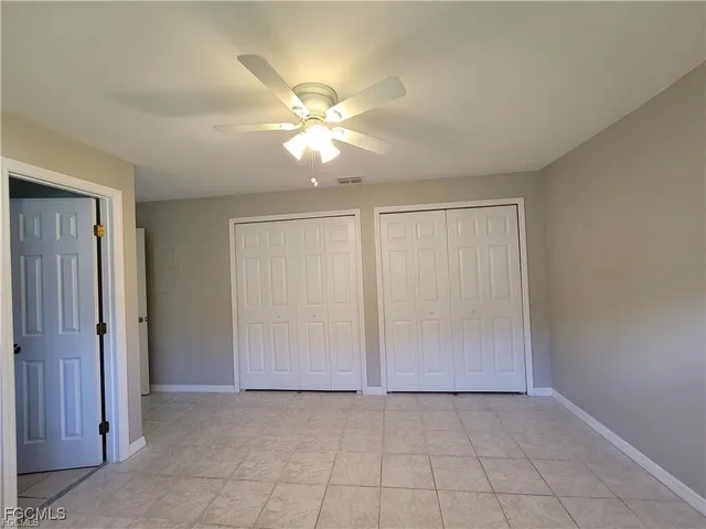 an empty room with closet and a chandelier fan