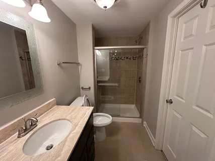 a bathroom with a granite countertop sink toilet and shower