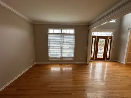 a view of an empty room with glass door and wooden floor