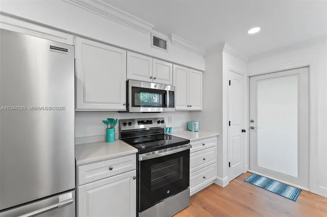 a kitchen with white cabinets and stainless steel appliances