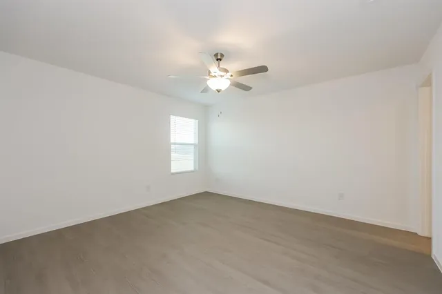 an empty room with a window and a ceiling fan