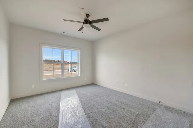 a view of an empty room with wooden floor and a kitchen
