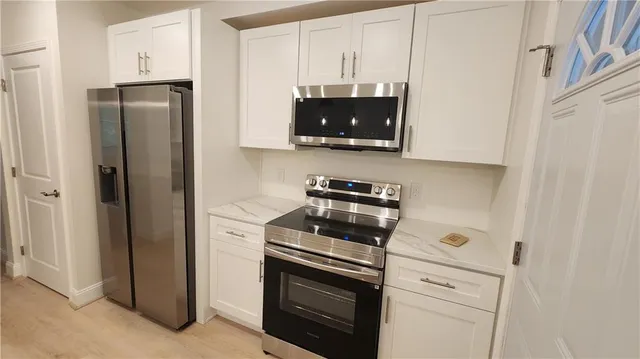 a kitchen with a refrigerator stove and white cabinets