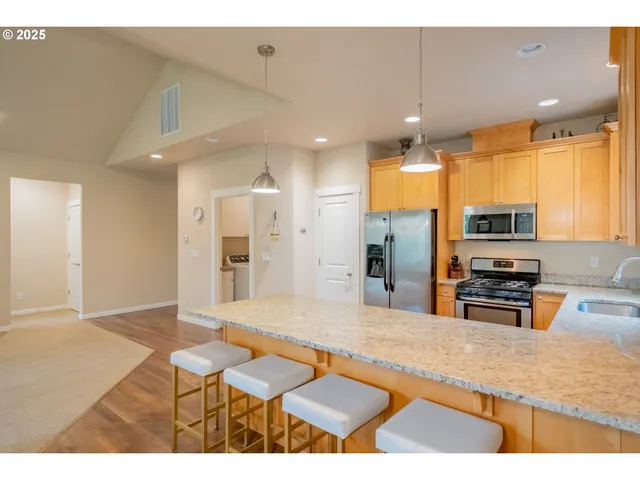 a kitchen with stainless steel appliances kitchen island granite countertop a refrigerator and microwave