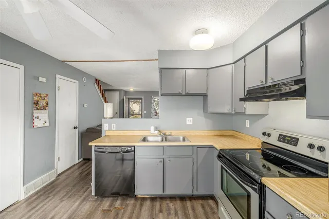 a kitchen with a sink a stove cabinets and wooden floor